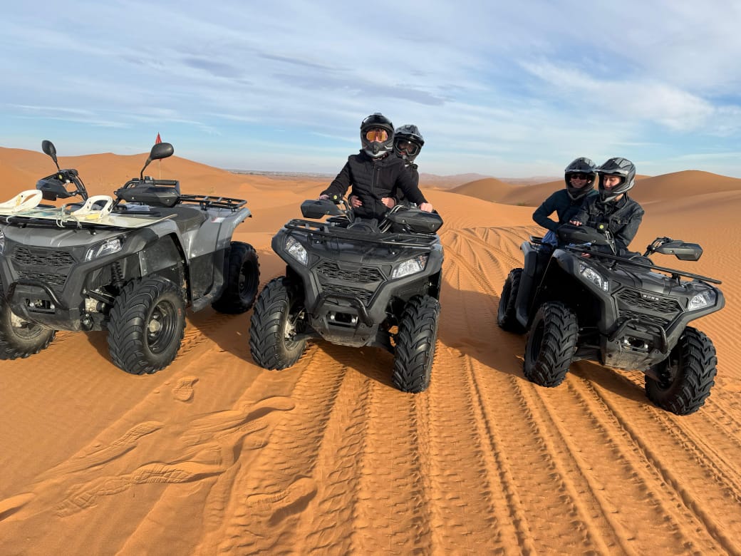 Travelers on quad bikes (ATVs) riding across the Erg Chebbi sand dunes
