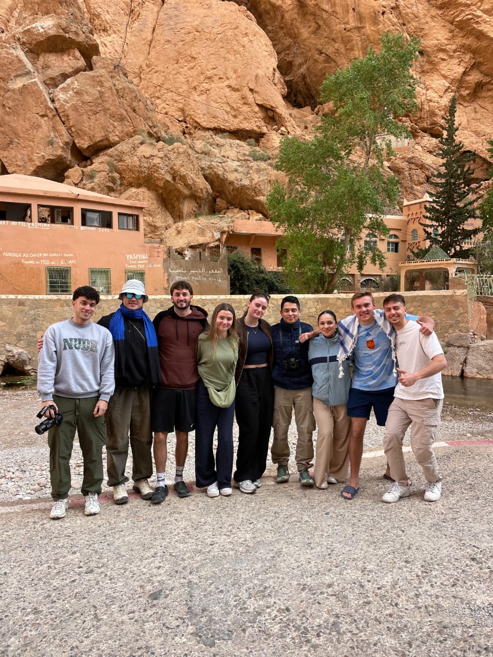Travelers and driver-guide at Todra Gorge beneath the red canyon walls